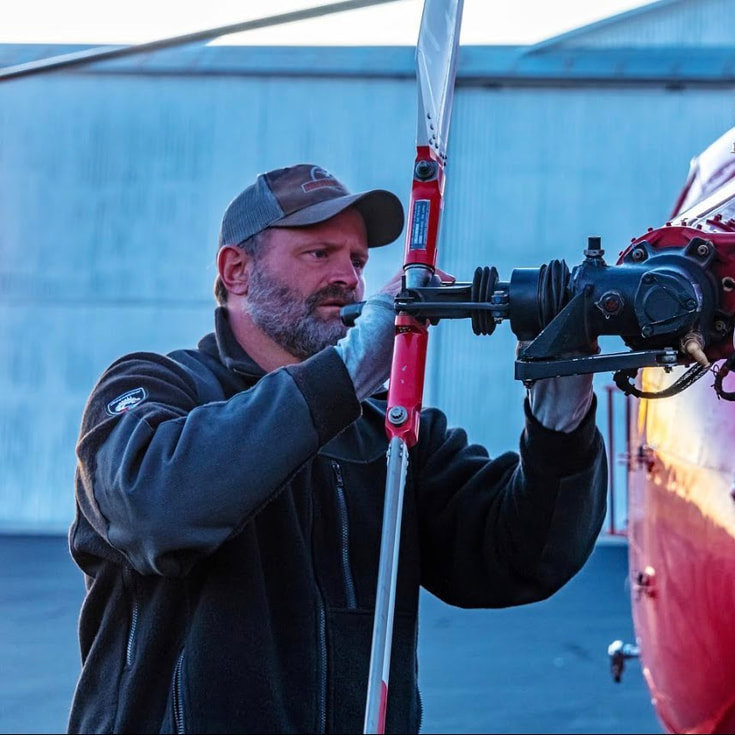 Phil Smith co-owner and chief pilot of Rotor Power performing helicopter maintenance on rotor assembly