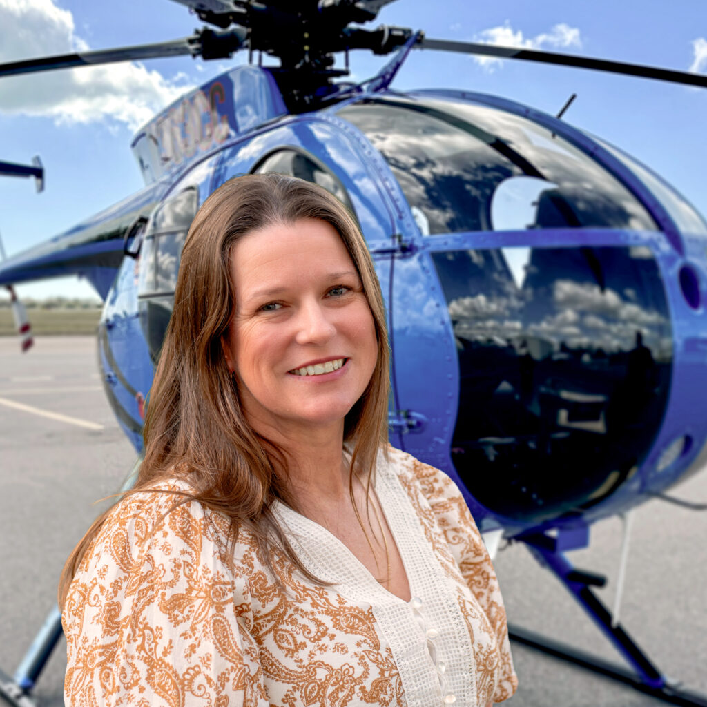 Kelly Smith co-owner and managing director of Rotor Power standing in front of company helicopter